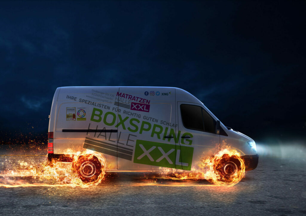 High-speed Lieferung mit Matratzenlieferdienst: BoxspringXXL Lieferwagen mit brennenden Rädern auf der Straße